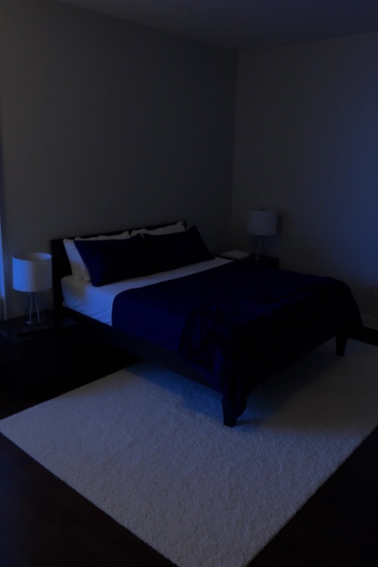 Bedroom with cool gray walls, navy bedding on a platform bed, bedside lamps, and white fluffy rug on wood floors
