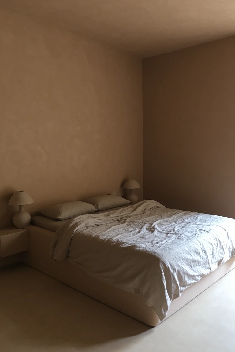 Bedroom with warm beige walls, platform bed in white linens, and paired bedside lamps on floating shelves
