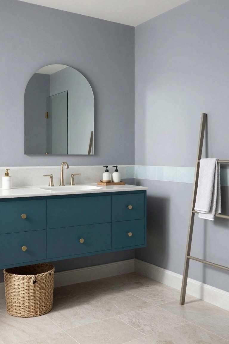 Bathroom with soft gray walls, navy vanity, and gold hardware.